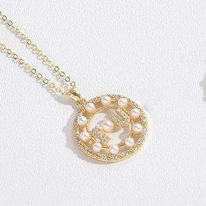 Detail of gold circle pendant with pearls, rhinestones and I U letter design