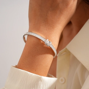 Close-up of a silver pavé-set diamond oval bangle worn with a white shirt