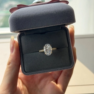 Macro shot of oval cut zircon ring with pavé diamond band in a velvet jewelry gift box