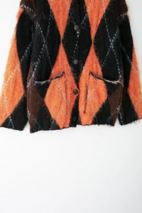 Gros plan du cardigan en maille à losanges avec motifs orange, noir et détails de poche