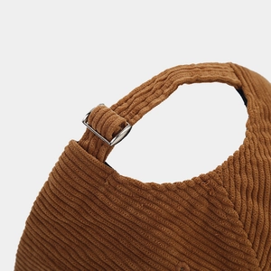 Dettaglio del cappellino in velluto a coste marrone con cinturino regolabile e fibbia in metallo