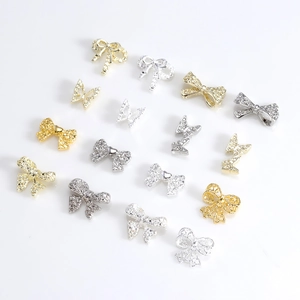 Golden and silver metal 3D bowknot nail charms with sparkling crystals on white background