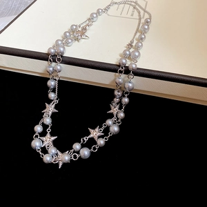 Close-up of grey pearls and silver star pendant on a double-layer necklace chain