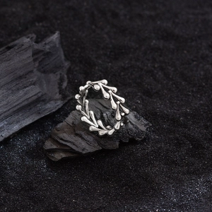 Irregular silver dragon bone heart ring placed on black volcanic rock texture