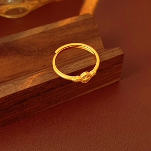 Dettaglio anello regolabile oro vintage con fiore a croce e finitura opaca su supporto
