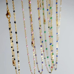 Detailed macro view of gold plated chain necklaces featuring colorful enamel bead accents