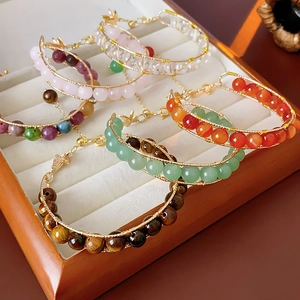 Detailed view of handmade tiger eye and crystal beaded bracelets with gold charms