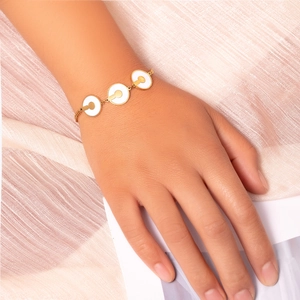 Dettaglio di un bracciale in titanio dorato con cerchi in madreperla su seta rosa
