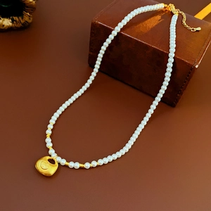 Detail of pearl necklace with gold lucky bag pendant and small golden spacer beads