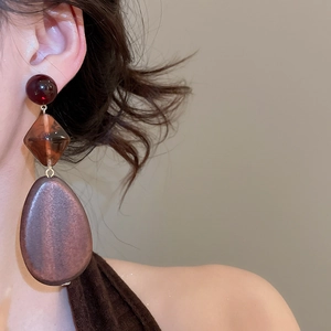 Macro shot of three-tier vintage drop earrings featuring amber and matte wood charms