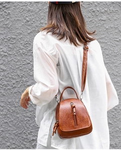 Rear view of model wearing the brown vintage faux leather crossbody bag on a white shirt