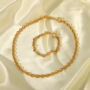 Polished gold stainless steel necklace and bracelet set with toggle clasp on silk