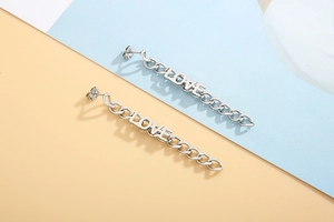 Close-up of polished silver metal long chain earrings with LOVE letter and tassel design