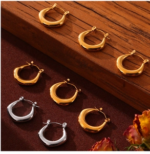 Détail des boucles d'oreilles en forme de U en or et argent sur des marches en bois