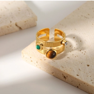 Détail d'une bague dorée ornée de malachite, œil de tigre et zircon brillant