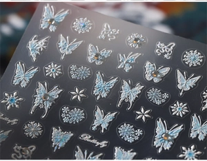 Macro shot of 3D embossed butterfly nail stickers with aurora blue and silver accents
