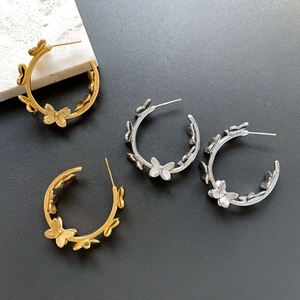 Elegant gold and silver butterfly C-shape hoop earrings on a textured stone surface