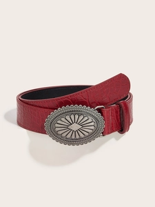 Detail of red crocodile pattern leather belt with vintage silver floral buckle on beige
