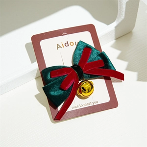 Detail of Christmas bow hair clip with velvet fabric, gold bell, and festive red green colors