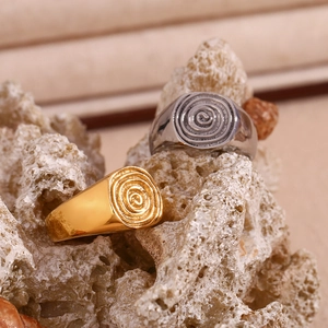 Detail view of gold and silver signet rings with spiral fingerprint patterns on rock