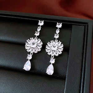 Detailed close-up of elegant silver drop earrings with floral zircons on a black display