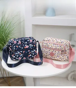 Detail view of navy floral and beige polka dot nylon crossbody bags with zip pockets