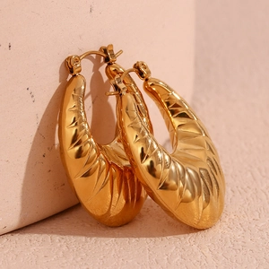 Macro shot of 18K gold plated hoop earrings featuring intricate hammered leaf-like textures