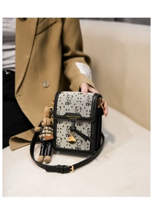 Detail view of canvas crossbody bag with bear pattern and cute teddy bear charm accessory