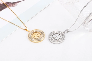 Detail of gold and silver necklaces featuring rotating clover pendants with crystal halo