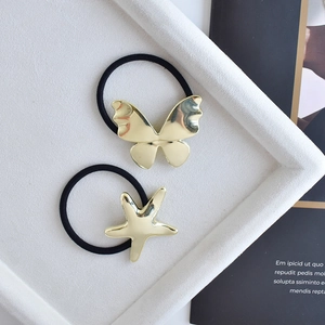 Minimalist gold butterfly and starfish hair ties set on an elegant textured tray