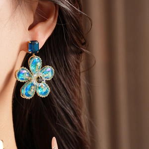Gros plan de boucles d'oreilles fleurs vintage dorées avec cristaux bleus sur mannequin