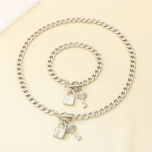 Vue détaillée de l'ensemble collier et bracelet à maille gourmette avec pendentifs clé et cadenas