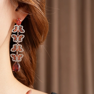 Détail de boucles d'oreilles vintage avec motif papillon rouge et gouttes en zircon