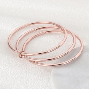 Detail of rose gold triple interlocking bangles in polished 3mm stainless steel finish