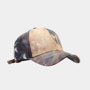 Gros plan sur la texture du coton tie-dye et les surpiqûres sur la visière de la casquette