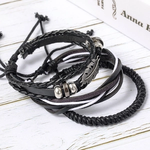 Detail of multilayer leather bracelets with feather pendant and beads on wood texture