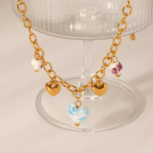 Detail of gold chain necklace featuring ceramic heart charms and floral sphere beads