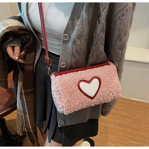 Détail du sac bandoulière en laine d'agneau rose avec patch cœur blanc et bandoulière rouge