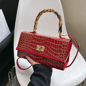 Detail of red crocodile pattern bag with premium bamboo handle and gold buckle clasp
