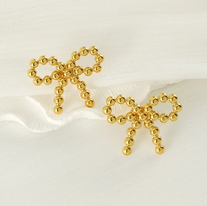 Close-up of 18k gold-plated stainless steel bead bow earrings on a white silk background