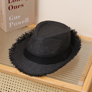 Detailed close-up of a black straw fedora featuring frayed edges and a silk ribbon band