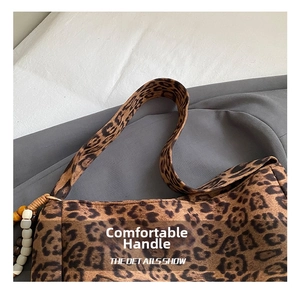 Detail view of leopard print shoulder bag handle and stylish beaded wooden charm
