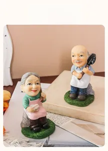 Dettaglio di statuette di coppia di anziani in resina con abiti da giardino vintage