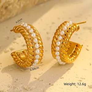 Macro detail of 18K gold-plated C-shape earrings with twisted metal and white pearl inlay