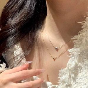Close-up of a double-layered titanium steel necklace with gold and silver heart pendants