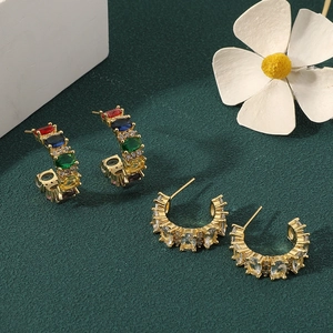 French vintage gold earrings with colorful zircon stones on elegant green background