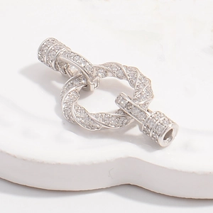 Macro shot of silver rope twist necklace clasp with cubic zirconia pave on ceramic tray
