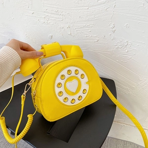 Detail of creative yellow telephone handbag with glossy patent leather and heart dial