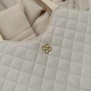 Sac fourre-tout matelassé beige chic avec emblème fleur dorée et texture premium