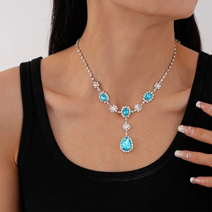 Macro shot of silver teardrop necklace with blue gems worn on a collarbone